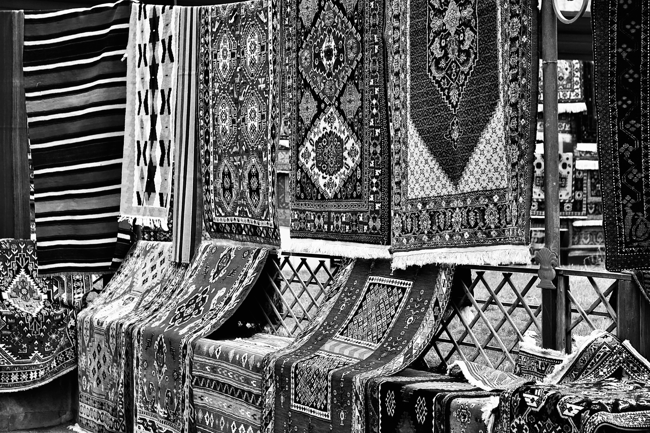 The Art of Drawing Readers In: Your attractive post title goes here A black and white photo of hanging traditional rugs in a market bazaar.