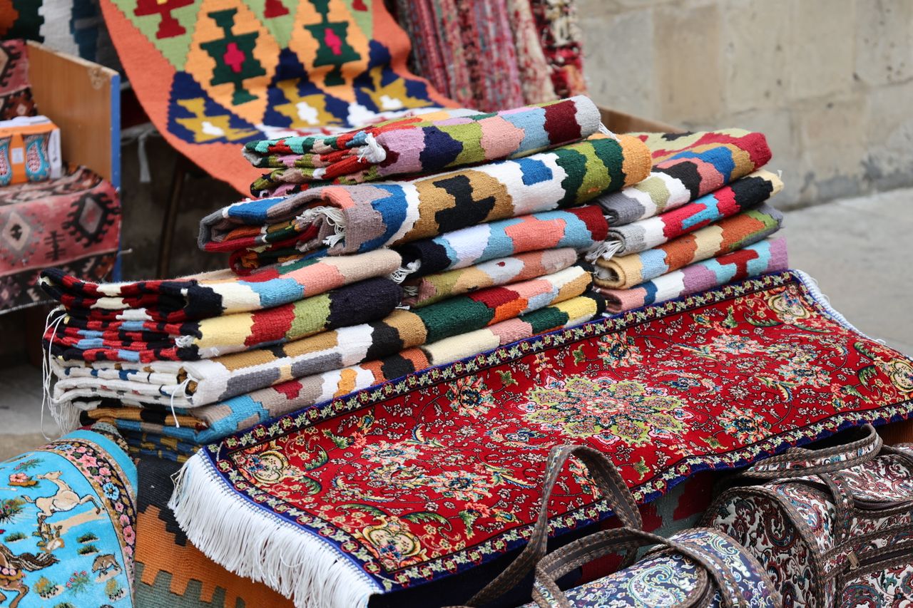 Crafting Captivating Headlines: Your awesome post title goes here Vibrant and diverse traditional woven rugs displayed in an outdoor market setting.